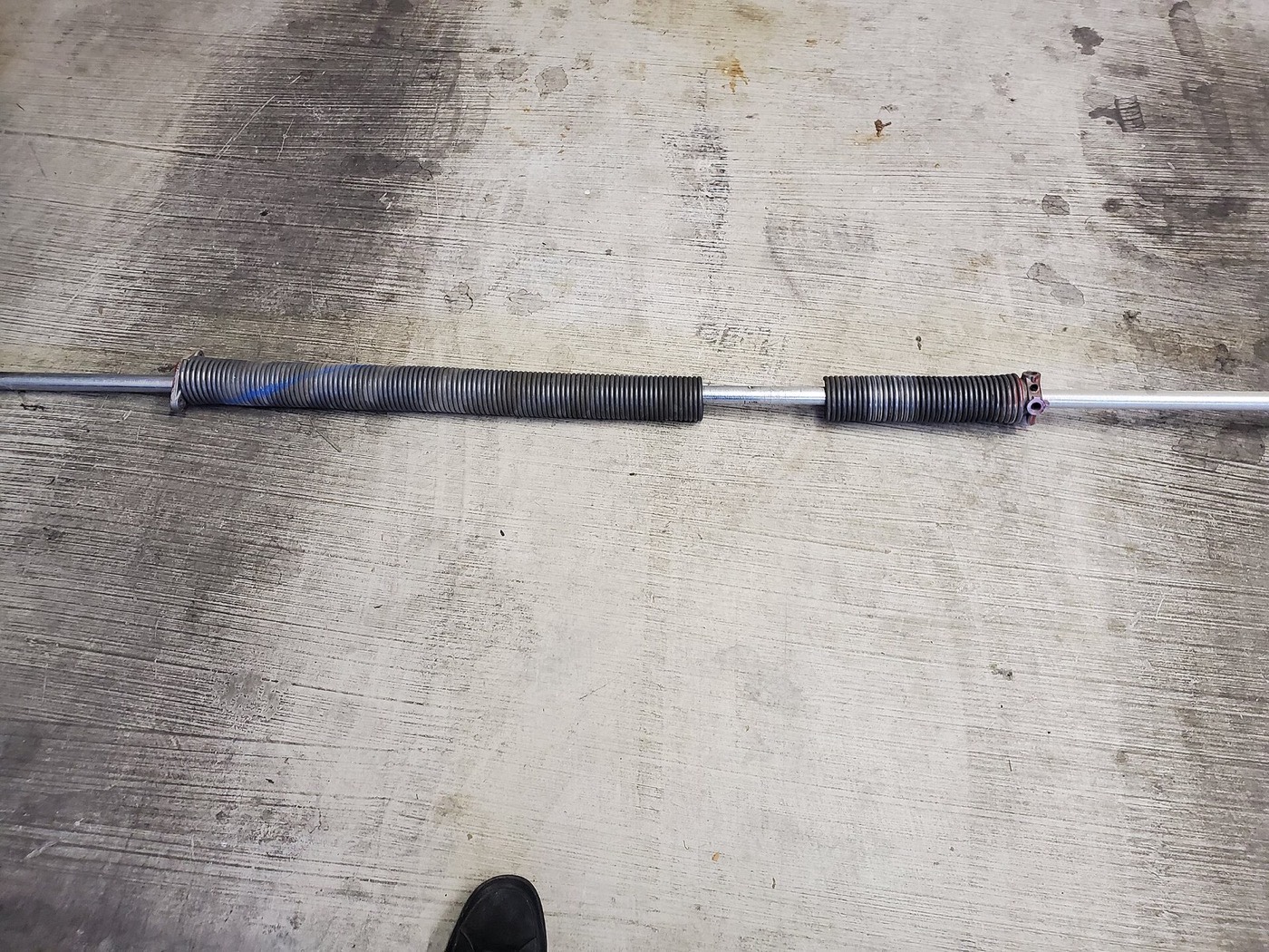 Failed garage door torsion spring with a separated coil, removed for replacement