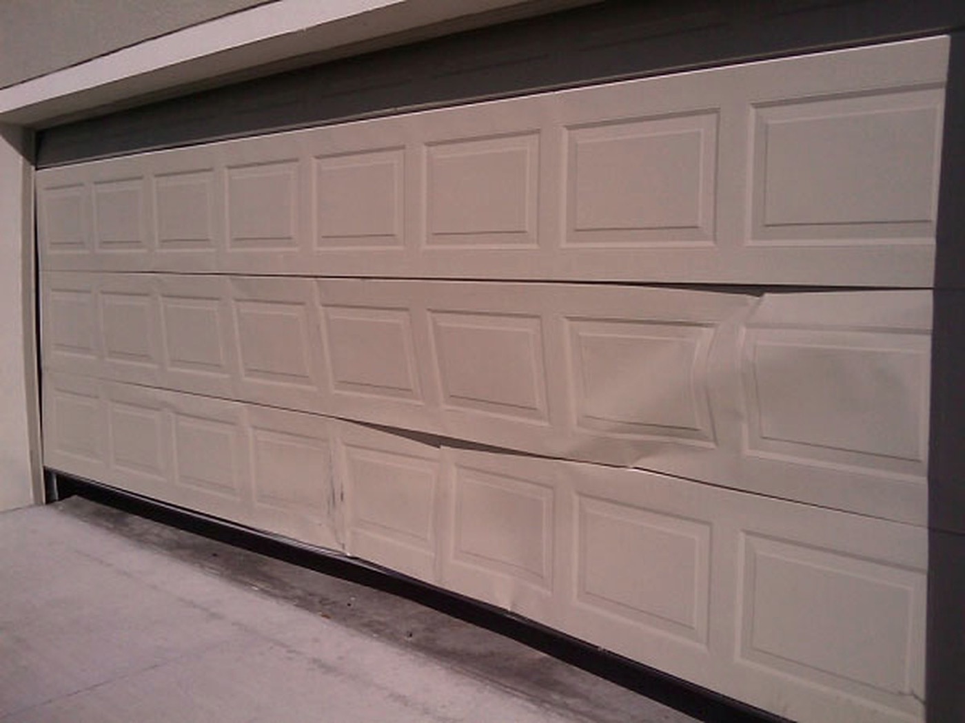 Dented residential garage door panel in need of repair or replacement