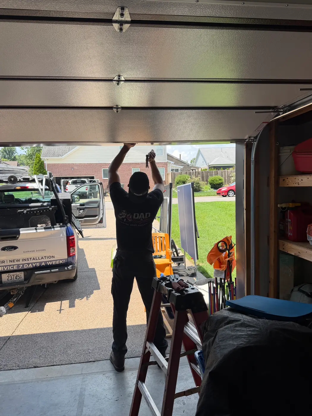 Dad & Daughter garage door project, technician carrying a new insulated garage door panel from the service van