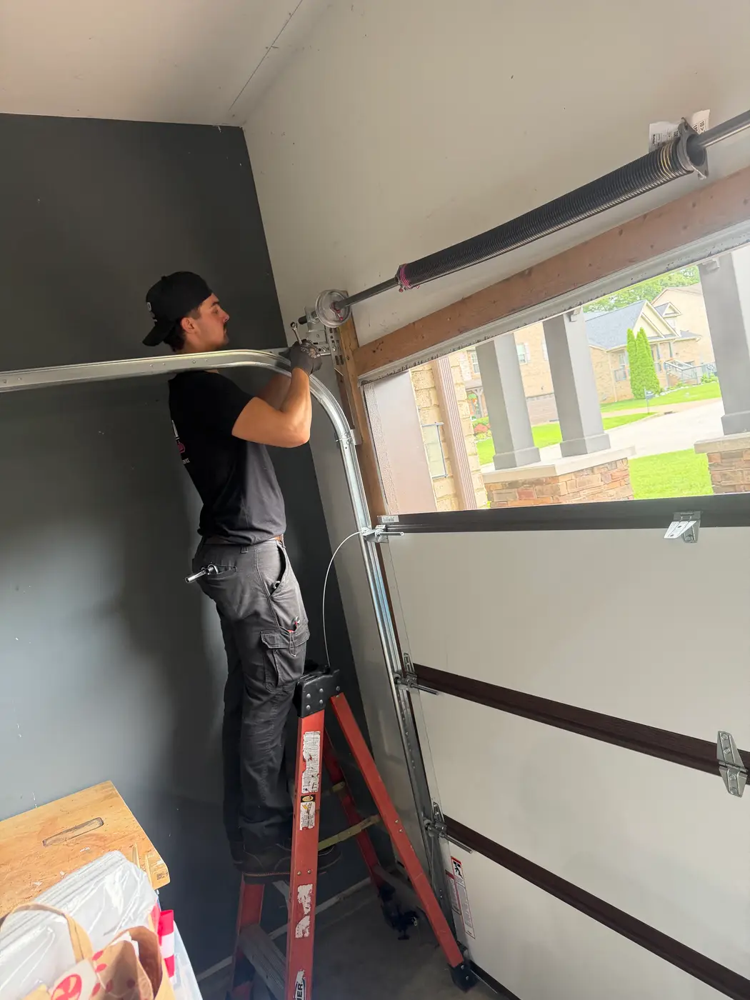 Dad & Daughter garage door project, technician on a ladder setting the top panel of a new garage door