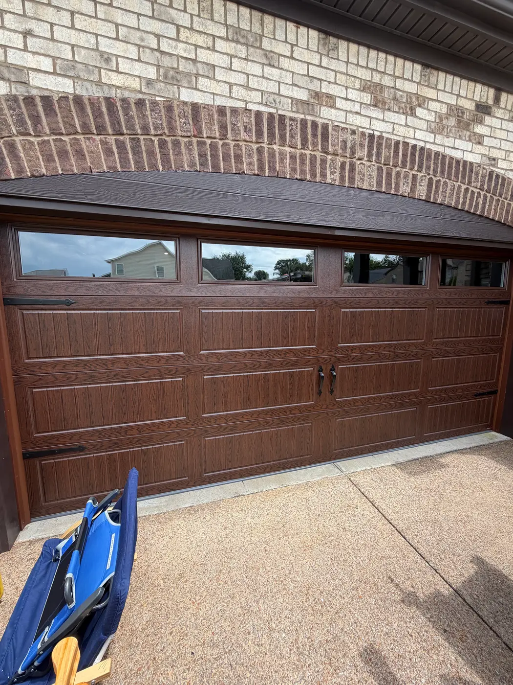 Dad & Daughter garage door project, walnut woodgrain carriage door with glass panels under a brick arch, new install