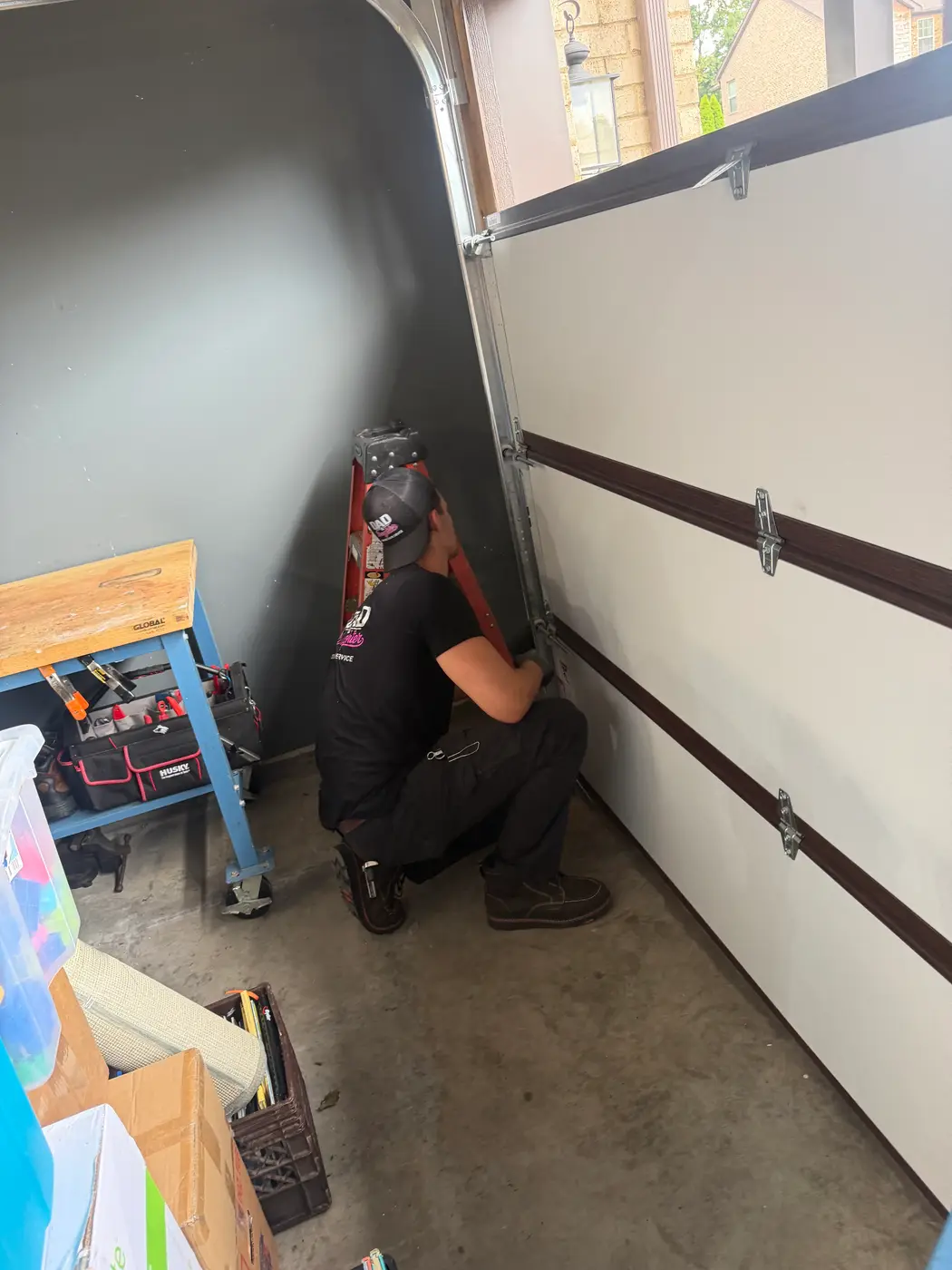 Dad & Daughter garage door project, technician adjusting the bottom section hardware of an insulated garage door