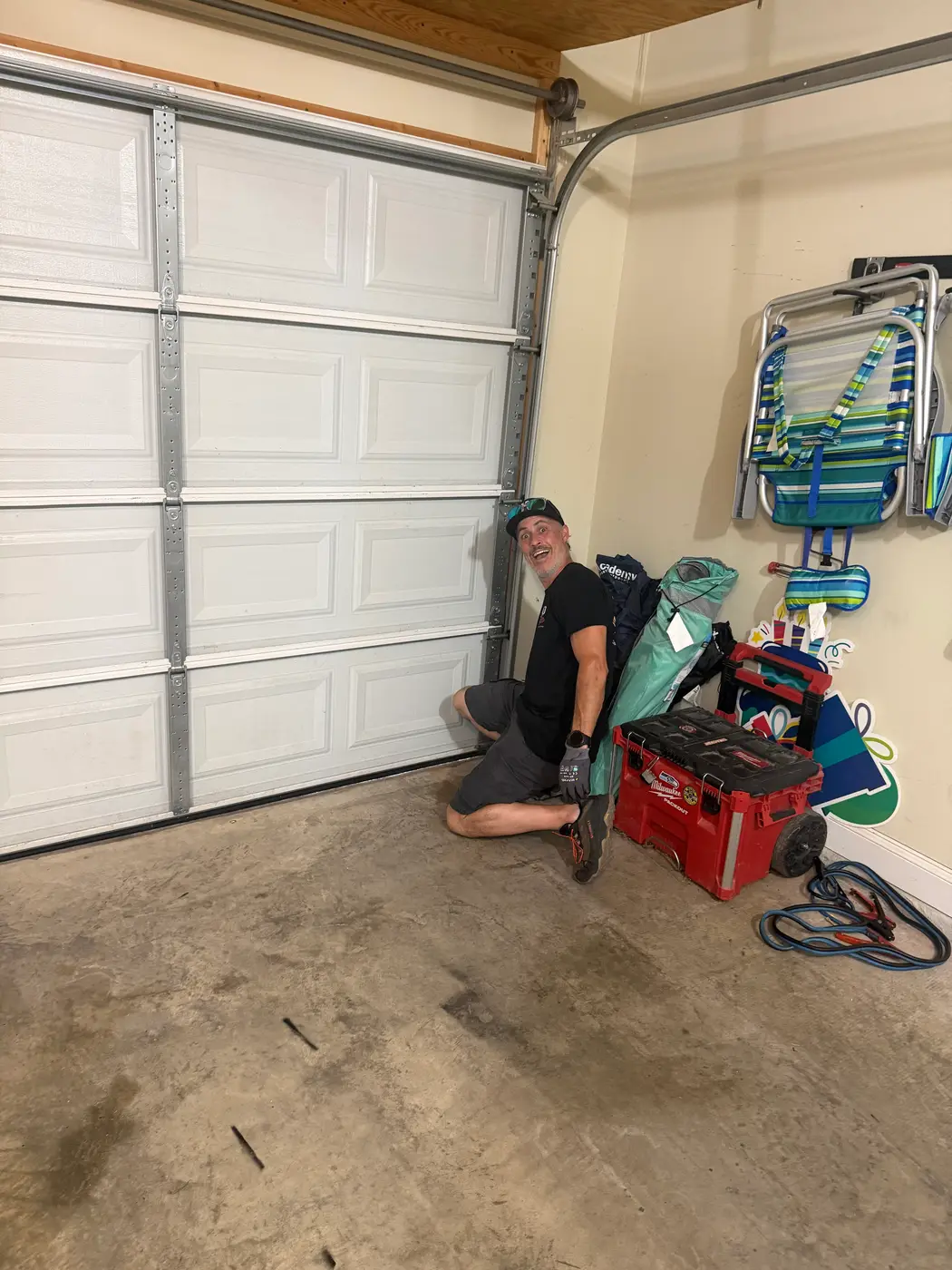 Dad & Daughter garage door project, technician servicing the bottom bracket and track of a white garage door